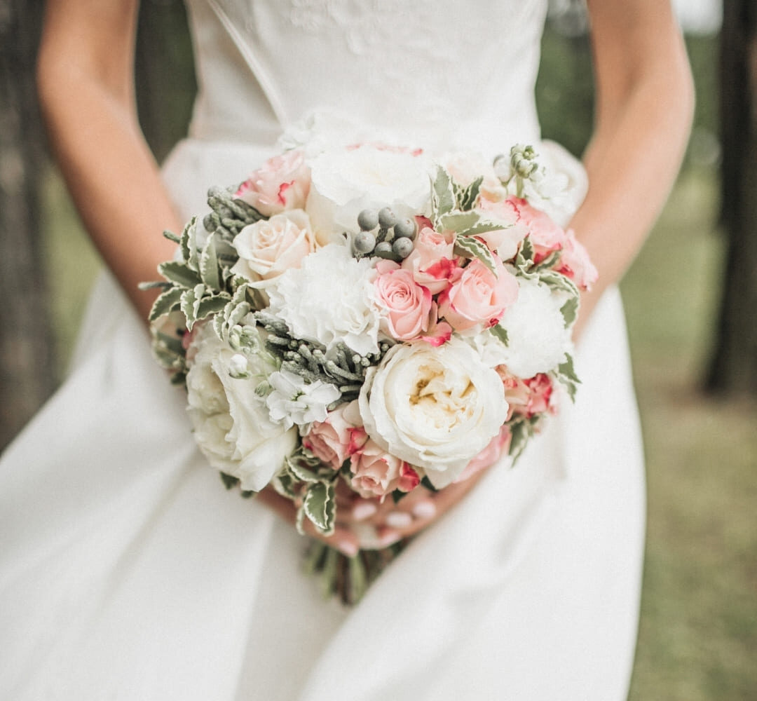 Mariée tenant un bouquet de fleurs blanches et roses aux finitions élégantes